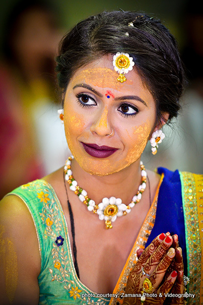 Indian Bride Applying Haldi on her Face during Pre Wedding Ceremony